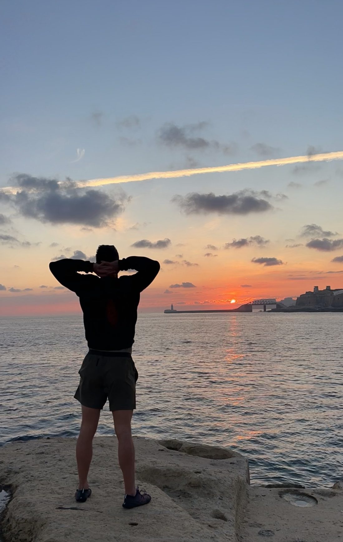 Fabien facing the sunrise over the sea in Malta